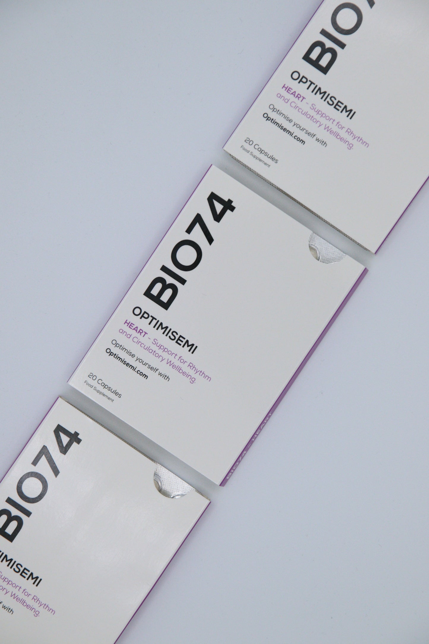 Image shows three diagonally arranged boxes of BIO74 OPTIMISEMI, a heart health supplement supporting rhythm and circulatory wellbeing. The clean, modern packaging contains 20 capsules per box.