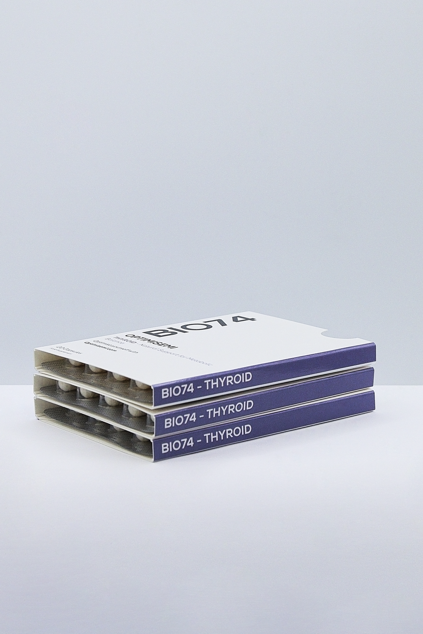 Image shows three neatly stacked boxes of BIO74 – THYROID, a thyroid supplement or medication with clean white and purple packaging, presented in an organized and professional manner.